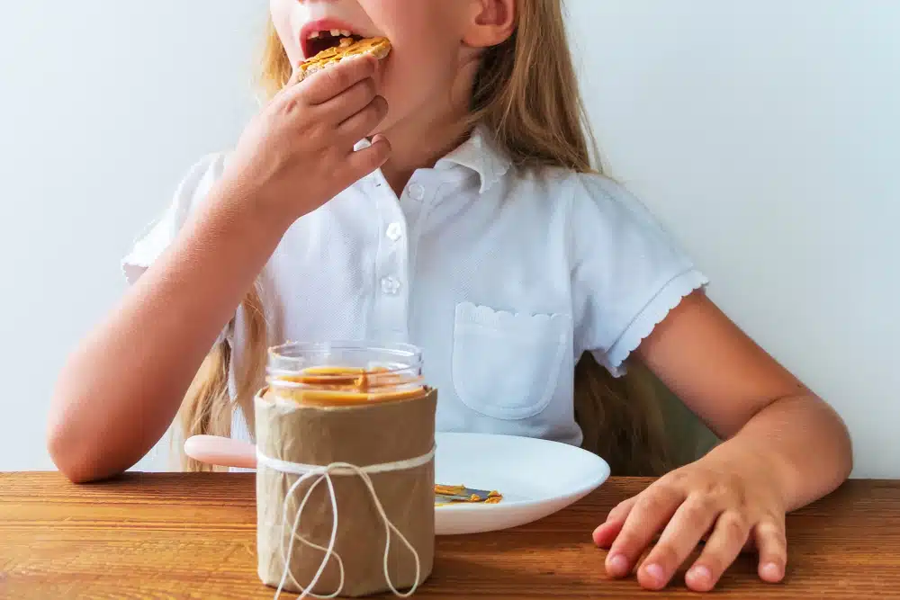 Child eating peanut butter toast highlighting food allergies in children.