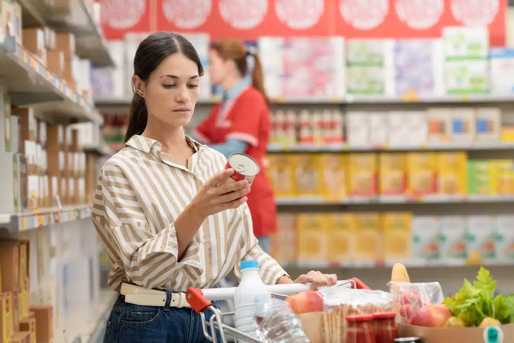 Woman reading food labels at grocery store to manage food allergies.